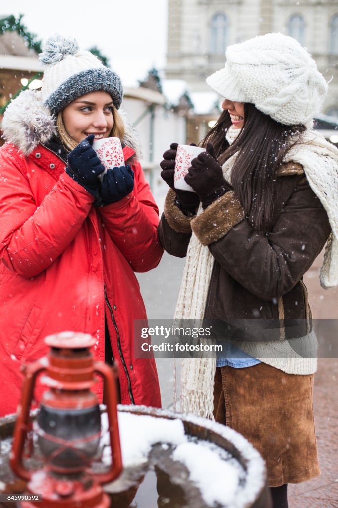 Freunde auf Weihnachtsmarkt trinken Punsch