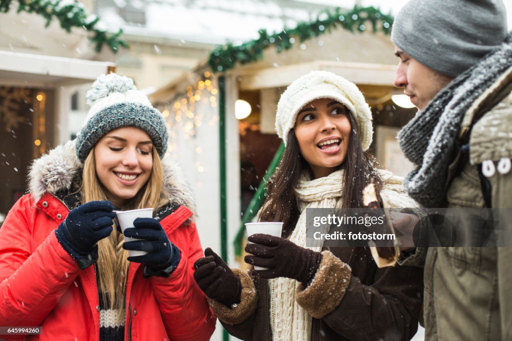 Friends eating and drinking at Christmas market