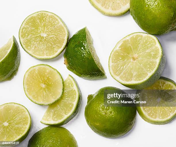 sliced limes on white surface - limone stock-fotos und bilder
