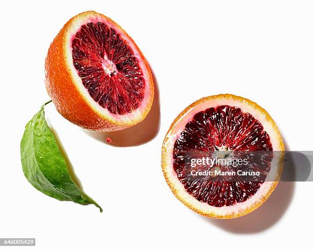 blood orange halves on white surface - bloedsinaasappel stockfoto's en -beelden