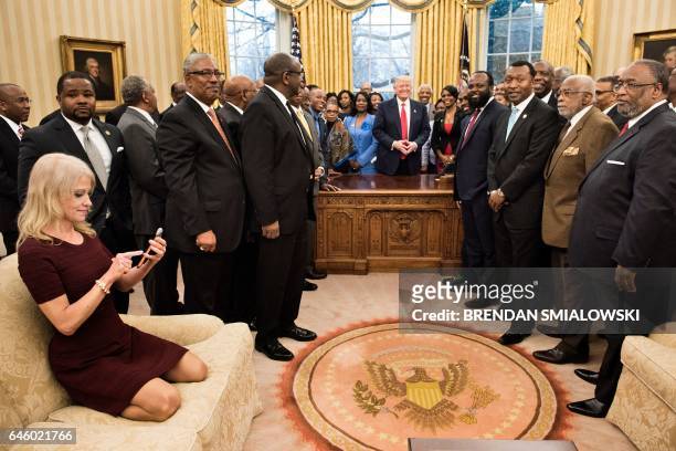 Counselor to the President Kellyanne Conway checks her phone after taking a photo as US President Donald Trump and leaders of historically black...