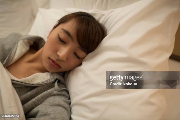 eine junge asiatische frau auf bett schlafen - bedzed stock-fotos und bilder