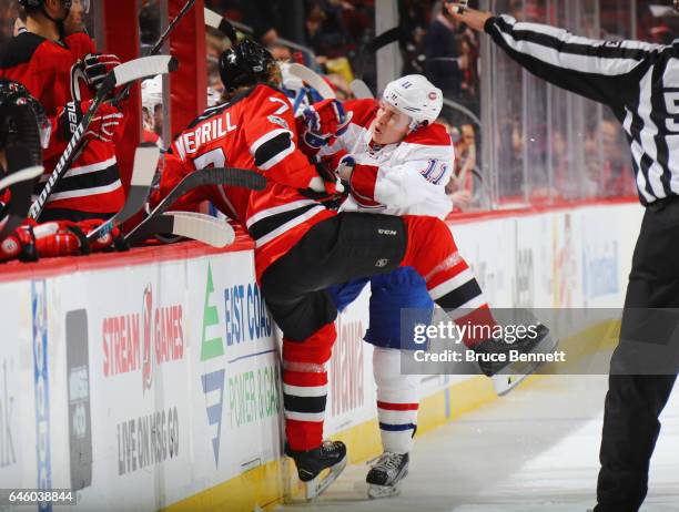Jon Merrill of the New Jersey Devils is checked into the boards by Brendan Gallagher of the Montreal Canadiens during the first period at the...