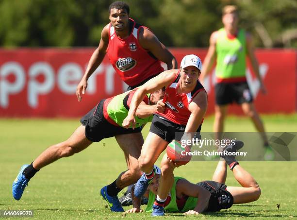 Jade Gresham of the Saints handballs whilst being tackled during a St Kilda Saints AFL training session at Linen House Oval on February 28, 2017 in...