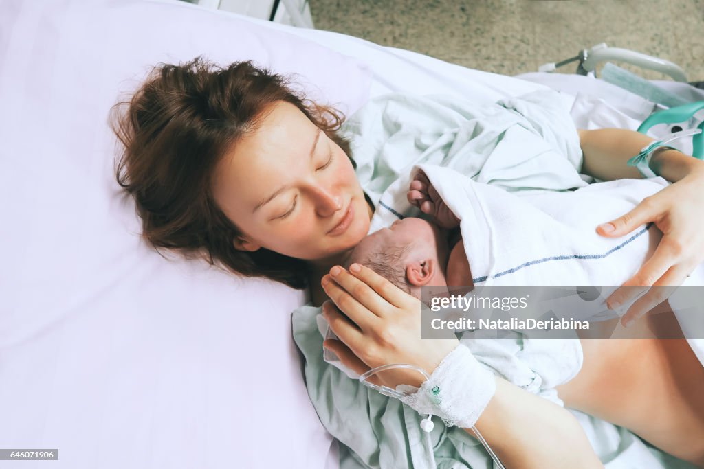 Mother holding her newborn baby child after labor in a hospital.