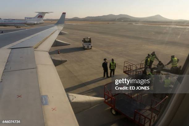 This photo taken on February 14, 2017 shows ground crew unloading luggage from a Tupolev Tu-204 aircraft at Sunan Pyongyang International Airport. /...