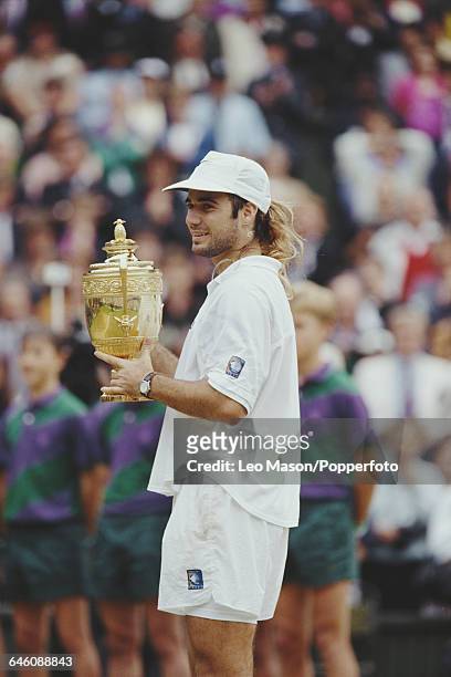 American tennis player Andre Agassi holds up the Gentlemen's Singles Trophy after defeating Goran Ivanisevic in the final of the Men's Singles...