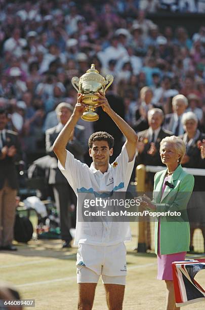 American tennis player Pete Sampras holds up the Gentlemen's Singles Trophy, presented by Katharine, Duchess of Kent, after defeating fellow American...