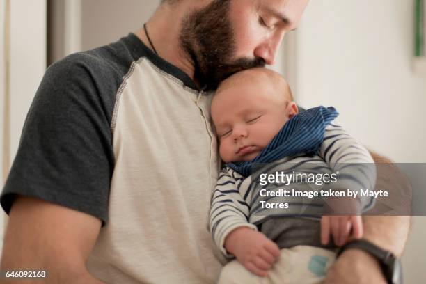 father kisses sleepy newborn - father holding sleeping baby stockfoto's en -beelden