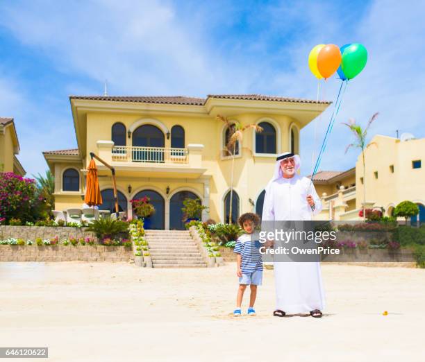 grand-vader en zoon met ballonnen op het strand - arab villa stockfoto's en -beelden
