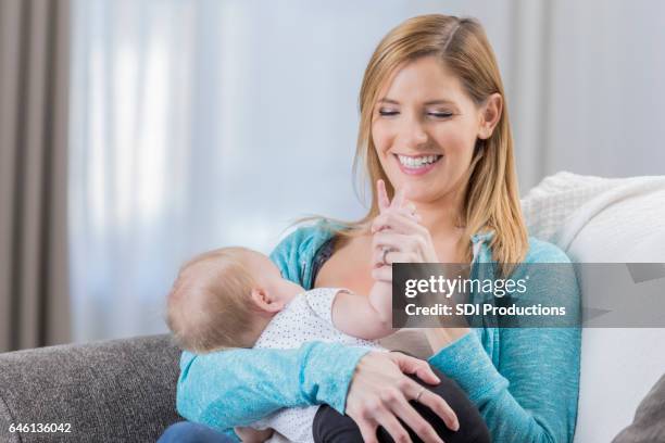 beautiful mom breastfeeds baby at home - suckling stock pictures, royalty-free photos & images