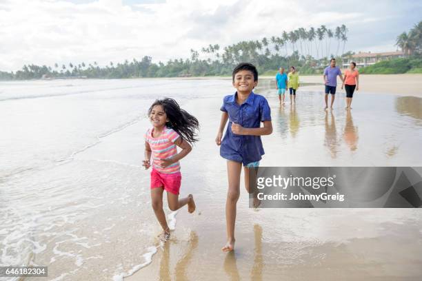 sister and brother running on sandy beach, smiling - sri lankan culture stock pictures, royalty-free photos & images