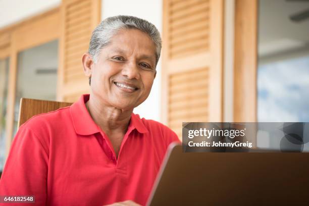 cheerful senior man with laptop smiling - tee srilanka stock pictures, royalty-free photos & images