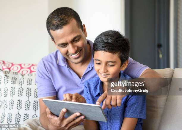 mid adult man helping boy use digital tablet - parent stock pictures, royalty-free photos & images