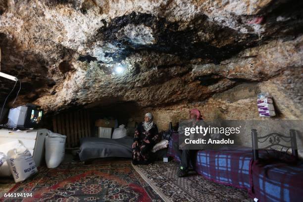 Palestinian family members watch television inside a cave using as a home after their sheds were demolished by Israeli bulldozers on 3rd January, on...