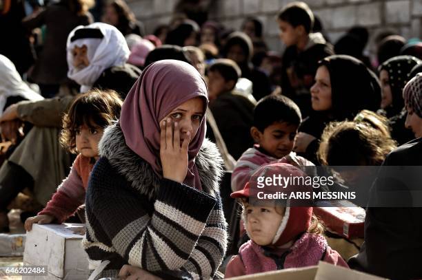 Displaced Iraqi young woman looks towards the camera as she gathers with others to flee the city of Mosul while Iraqi forces battle against Islamic...