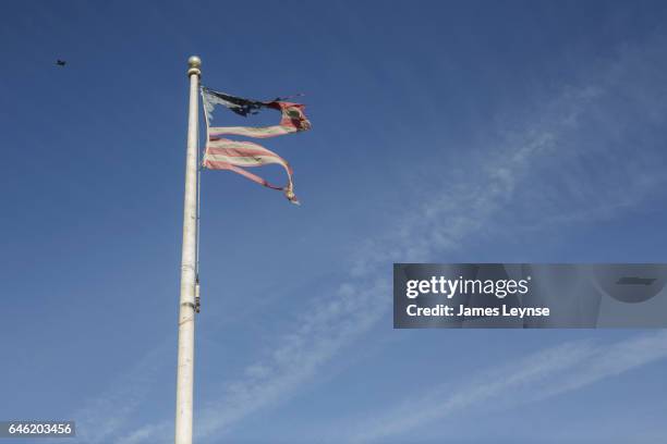 a tattered stars and stripes flag flying over a blue sky - 老朽化 ストックフォトと画像