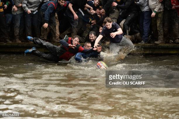 Competitors from the opposing teams, the Up'ards and the Down'ards, jump into the water and reach for the ball during the annual Royal Shrovetide...