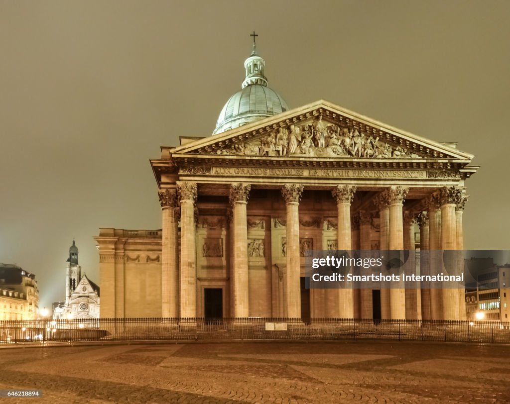 Paris Pantheon illuminated at night with church of Saint Etienne du Mont church on background, France