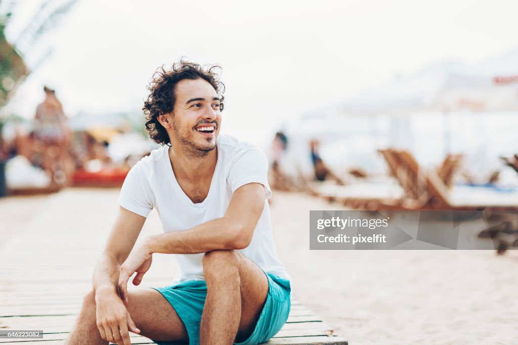 Cheerful man sitting outdoors in beach resort