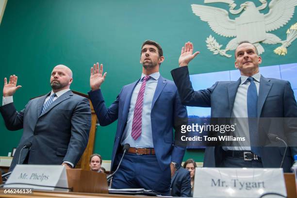 From left, Olympic gold medalists Adam Nelson and Michael Phelps, and Travis Tygart, CEO of the U.S. Anti-Doping Agency, are sworn in during a House...
