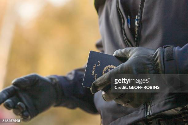 An RCMP officers holds the passport of a woman from Eritrea after she illegally crossed the US-Canada border near Hemmingford, Quebec, February 28,...