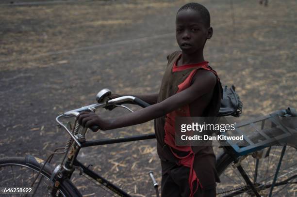 Young South Sudanese boy pushes his bike through a refugee settlement on February 25, 2017 in Palorinya, Uganda. After registering their details...