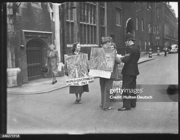 Policeman remonstrates with artists who are demonstrating against atomic bombs outside the house where the North Atlantic Treaty Council are meeting...