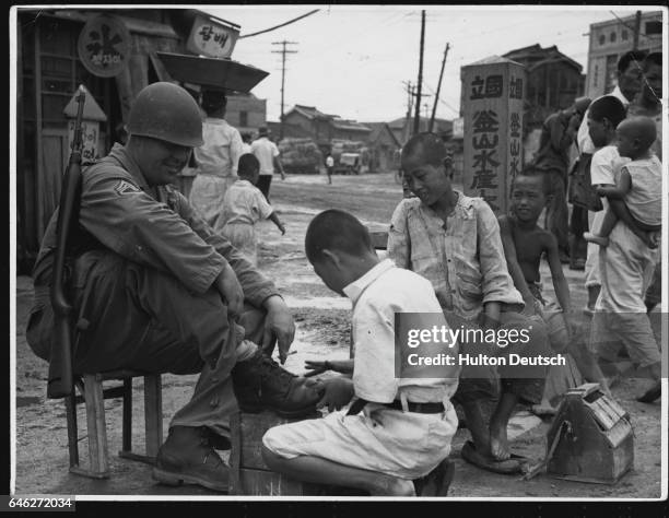 American Sergeant Receives A Shoe Shine. An American sergeant is seen having a shoe shine by a South Korean boy after his arrival in the town of...