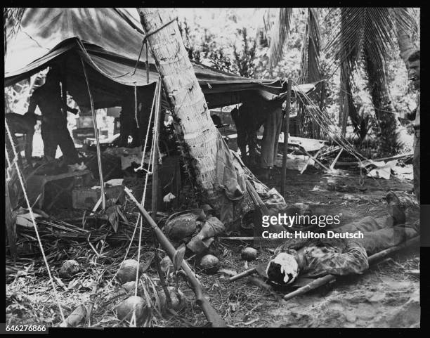 Wounded marine with a piece of shrapnel in his brain lies patiently on a litter outside an improvised hospital on Bougainville, 1944.