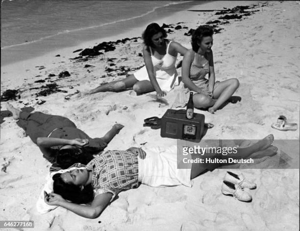 Group of young women sunbathe while listening to a radio on sandy Palm Beach, Florida, U.S.A. Ca. 1941.