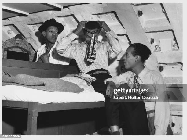 In their bedroom in the Clapham Shelter, Kenneth Murray, Eric Drysdale and Aston Robinson, recently immigrants from Kingston, Jamaica, adjust their...