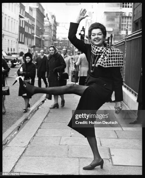 American film actress Rosalind Russell performing high kicks for the press, outside Claridge's Hotel, London, 1971.