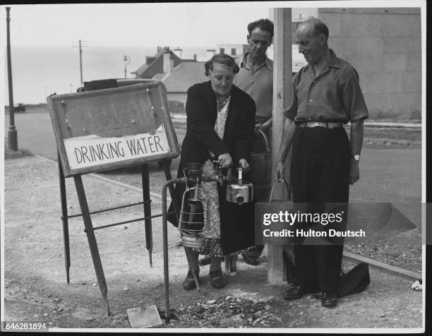 Resident of Saltdean fills a kettle with drinking water from a roadside pipe, set up during a water shortage. | Location: Saltdean, Sussex, England,...