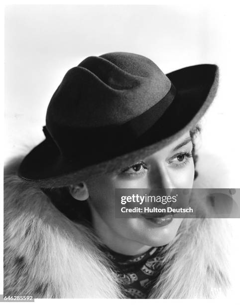American film actress Rosalind Russell modelling a felt hat with fur under brim, ca. 1940.