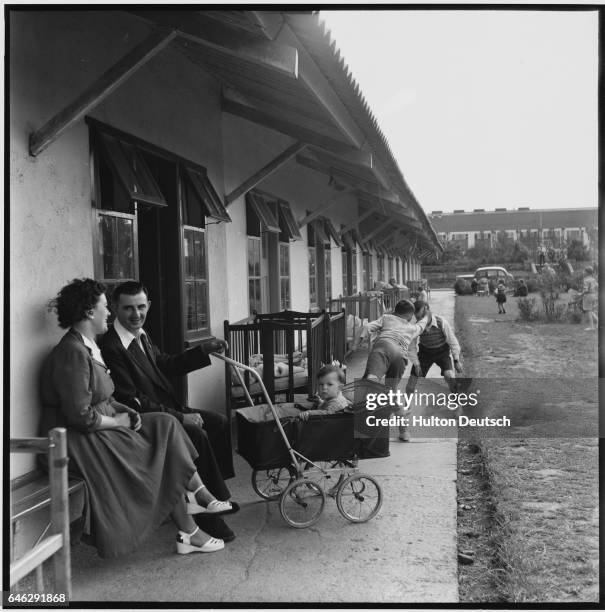 Campers sit outside their chalet talking, playing, and enjoying their visit at the Butlin's Holiday Camp in Filey, England.