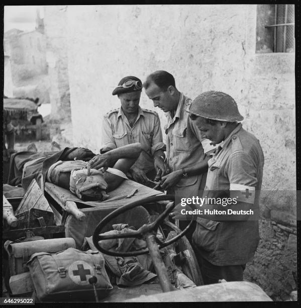 Captain L. O. Alexander of Calgary, Captain J. H. Slater of Halifax and Captain D. G. Thwaites of Toronto prepare to take a badly wounded German...