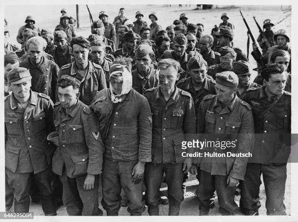 German Prisoners From Cherbourg Area. A very mixed group of German prisoners captured near Cherbourg. Some are wounded, a few seem quite content with...