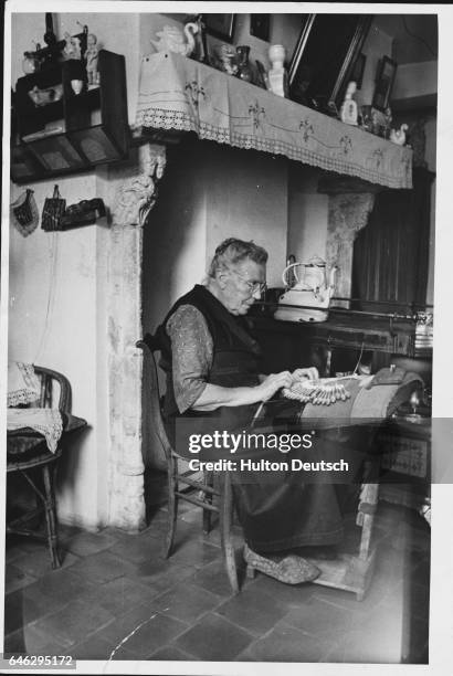 Woman makes lace in the kitchen of her Bruges home.