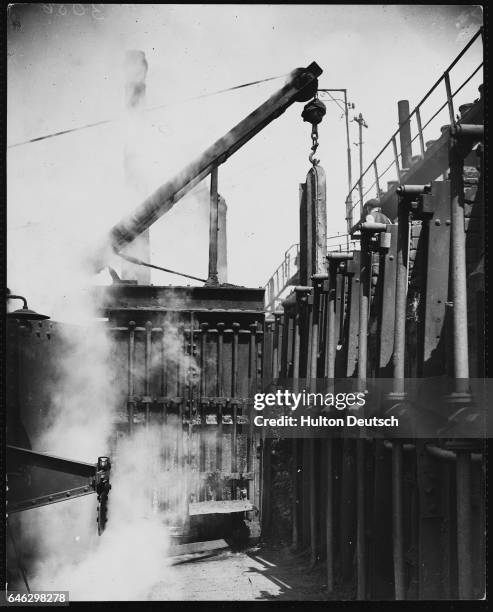 Coke oven door is raised and coke cake passes into a cooling tank.