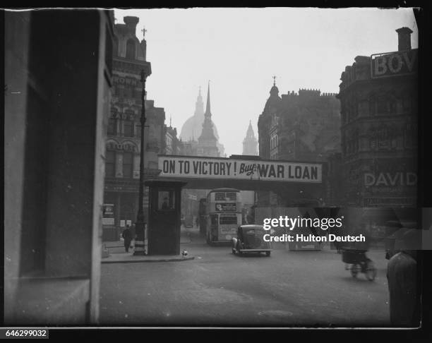 An advertisment plastered to a bridge in Ludgate Circus encourages the purchase of government bonds to raise war funds. London, March 1940.