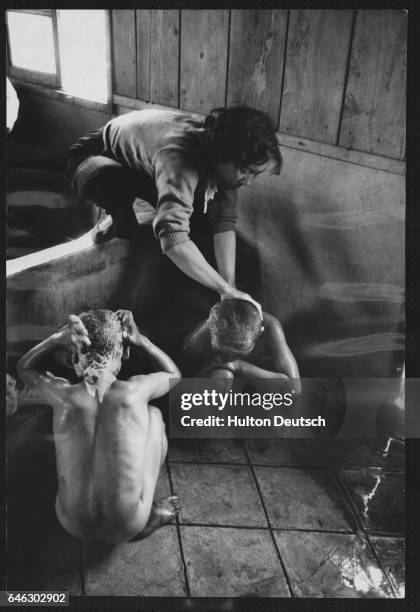 Two young boys are given a bath upon their arrival at the Children's Protective Home which provides both schooling and medical attention for needy...