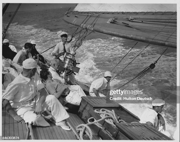 Mr. Andrea controls the wheel on board the Candida yacht competing in a race at the Cowes Regatta. | Location: Near Cowes, Isle of Wight, England, UK.