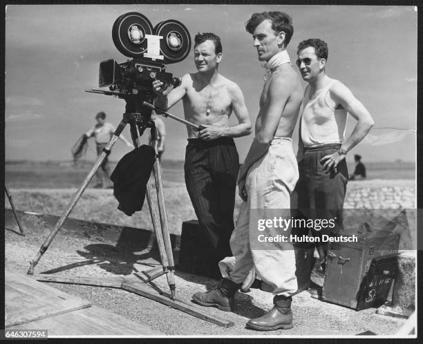 English actor John Mills with film cameramen during the making of the film The Long Memory, on location at Chitney Marshes, Kent, England, 1952. |...