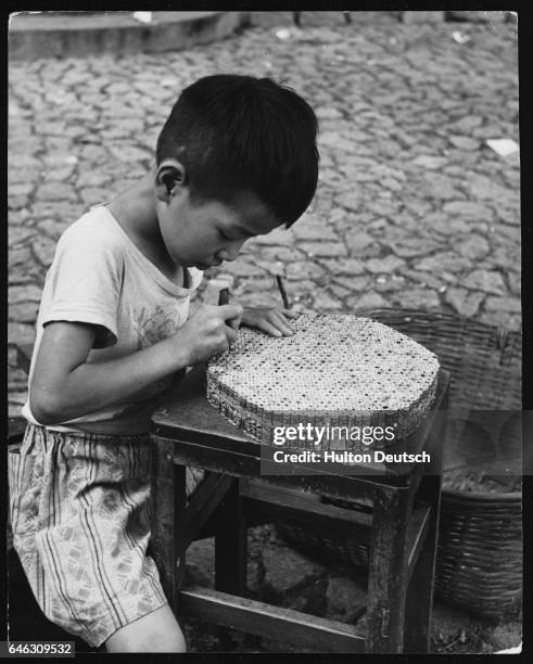 Small boy pierces fireworks with a small steel pin to make the holes in which the gunpowder will be poured and the fuses attached.