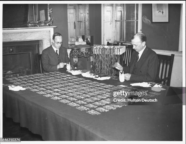 The Secretary of the Royal Almoner and his assistant prepare the purses of Maundy Money at Queen Anne's Gate, London. These will then be given to the...