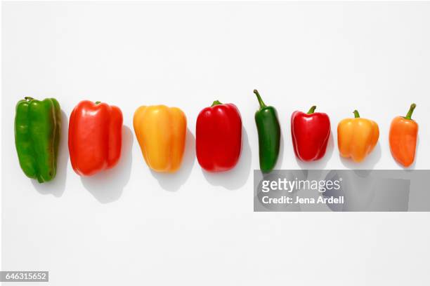line of bell peppers on white - gele paprika stockfoto's en -beelden
