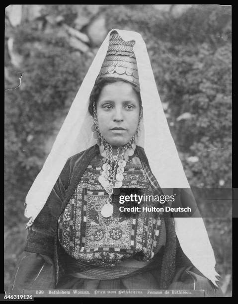 Young woman from Bethlehem wears a traditional headdress and embroidered gown.