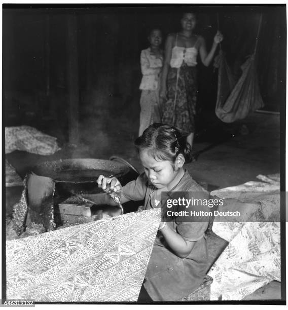 Girl applying wax to a sarong to draw a design into the cloth. Bali, 1954.