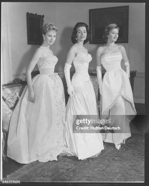 English actresses June Laverick, Anne Heywood, and Jill Ireland model the gowns they will wear at the Royal Film Performance, London, 1957. The...